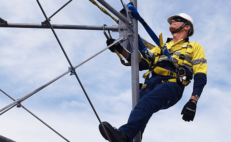 Técnico con arnés y casco trabajando en altura con línea de vida instalada
